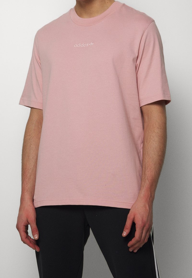 Vaaleanpunainen puuvillapaita, jossa on pyöreä pääntie ja lyhyet hihat. Rinnassa valkoinen adidas-logo. Pehmeä pinta, mukava istuvuus.