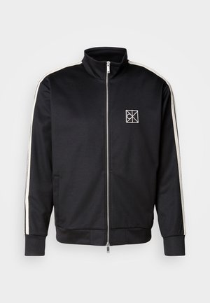 Zwarte zip-up jas met een hoge kraag, voorzien van witte zijstrepen en een klein logo op de borst, gemaakt van een soepel, flexibel materiaal.