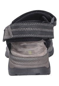 Sandale noire avec sangle réglable, dessus texturé, semelle intérieure rembourrée et semelle extérieure en caoutchouc. Caractéristiques : accents cousus et matériaux durables.