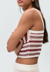 Top corto lavorato a maglia con una base bianca e righe orizzontali in bordeaux e lavanda. Ha spalline sottili e un design a trama aperta e testurizzata.