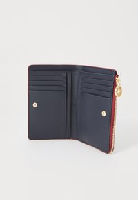 Intérieur d'un portefeuille en cuir bleu marine et rouge avec plusieurs emplacements pour cartes, un bouton pression doré et une fermeture éclair.