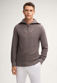Sweter w teksturowanym, taupe'owym dzianinie z kołnierzem na ćwierć zamka. Posiada ściągacz u dołu i przy rękawach, prezentując wzór w bloki.