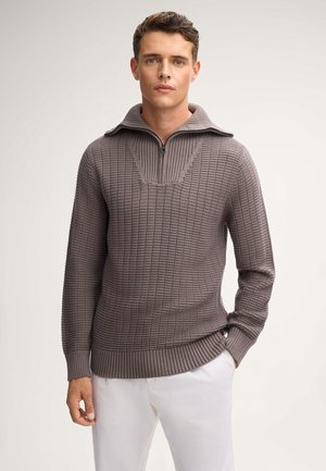 Sweter w teksturowanym, taupe'owym dzianinie z kołnierzem na ćwierć zamka. Posiada ściągacz u dołu i przy rękawach, prezentując wzór w bloki.