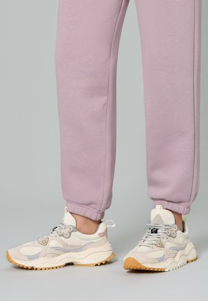 Scarpe da ginnastica beige chiaro con tessuto testurizzato, design con lacci e suola in gomma. Indossate con pantaloni aderenti lavanda.