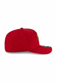 Red baseball cap with a structured crown, curved brim, and embroidered design on the front. Features ventilation holes and a snapback closure.