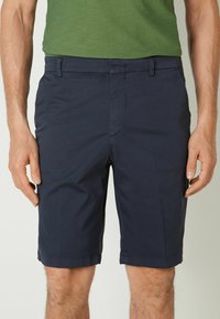 Mörkblå shorts i lätt material, med sidofickor och platt frontdesign, med en fin fåll och subtil textur.