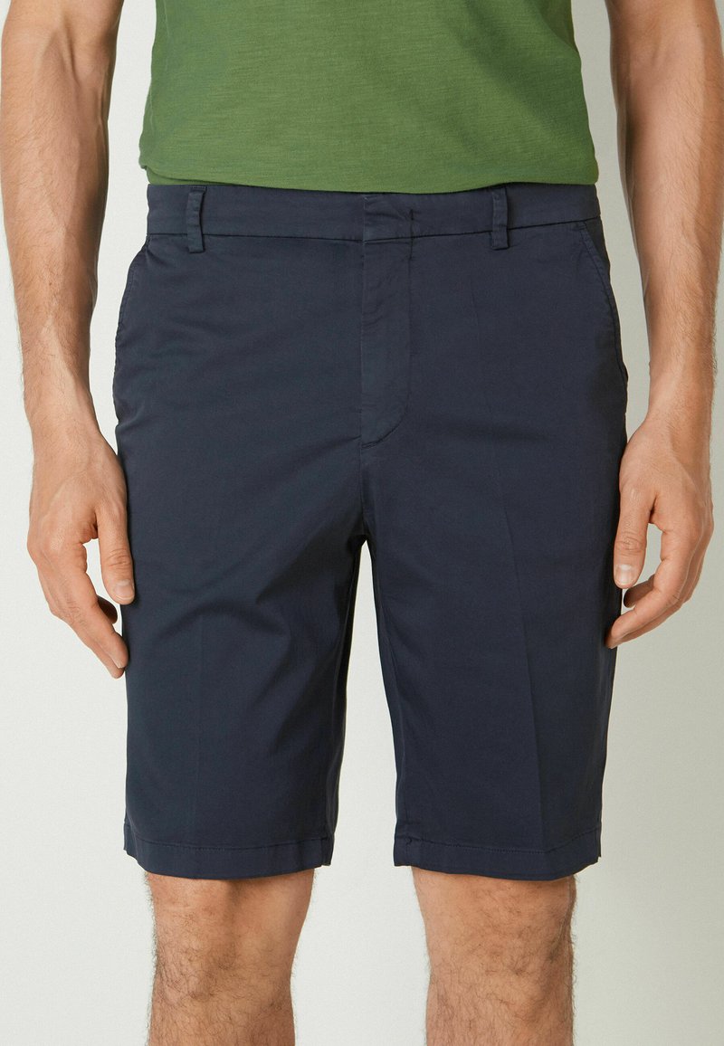 Mörkblå shorts i lätt material, med sidofickor och platt frontdesign, med en fin fåll och subtil textur.