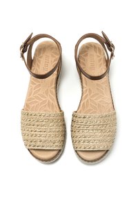 Sandales à brides en cuir tan avec une tige en fibre naturelle tissée. La semelle intérieure présente un motif de feuilles. Fermeture à boucle au niveau de la cheville.