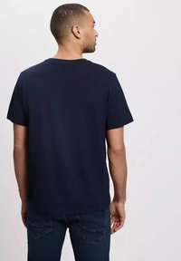 Granatowa koszulka z krótkim rękawem z okrągłym dekoltem, wykonana z miękkiego materiału. Posiada prosty design bez widocznych logotypów czy wzorów.