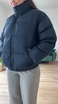 Black puffer jacket with a high collar, zip closure, and elasticated hem. Features a small Levi's logo on the front. Soft, quilted texture.