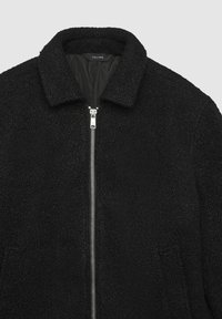 Schwarze Zip-Jacke aus strukturiertem Stoff, mit Kragen und silbernem Reißverschluss, mit einem warmen, weichen Erscheinungsbild.
