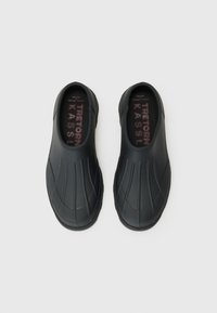 Black slip-on shoes with a smooth rubber finish, featuring ribbed detailing and a padded insole with brand name in contrasting red text.