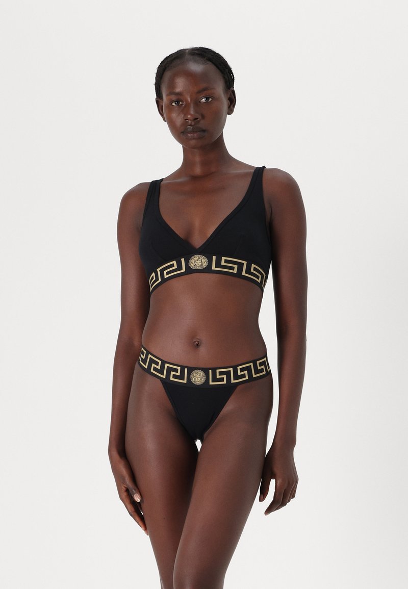 Black bikini set with a textured gold Greek key pattern and emblem on the band. The top features a deep V-neck design.