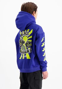 Blauwe hoodie met een grafische print van gestileerde aapjes en de tekst "BLACK BANANAS". Bevat gele bliksemschichten en een voorkantzak.