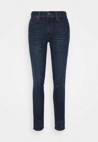 Mörkblå denimjeans med slim fit, fem fickor, metallknäppning och synlig söm längs kanterna. Slät yta.