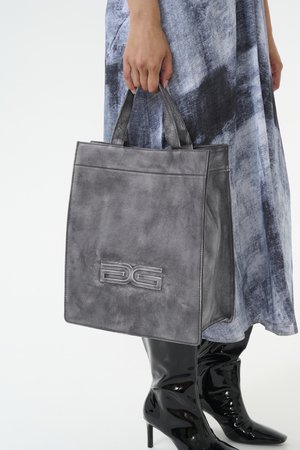 Bolso tote de piel gris con logo embosado, diseño plano y doble asa. La textura parece suave con un brillo sutil.