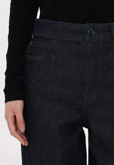 Dark blue denim jeans with a straight cut, featuring a classic button closure, front pockets, and a subtle herringbone texture.
