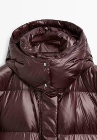 Donker maroon pufferjack met een hoge glanzende afwerking en een hoog gewatteerd kraag die is bevestigd met twee zwarte drukknoopjes.