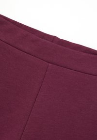 Bordeaux katoenen leggings in een blend met een gladde textuur, voorzien van een brede tailleband en platte naden voor comfort. Geen zichtbare patronen of accenten.