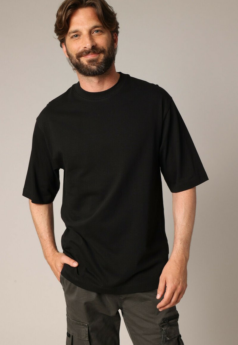 T-shirt noir à manches courtes en coton doux, featuring un design classique à col rond. La coupe est décontractée, avec une texture lisse.