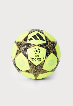 Geltona UEFA Čempionų lygos futbolo kamuolys su juodais akcentais ir detalia grafika, su išsiskiriančiu logotipu centre ir žvaigždžių raštu.