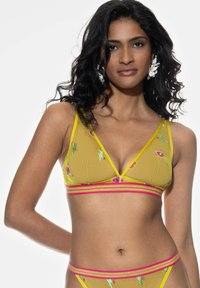 Żółty siatkowy biustonosz braletka z kwiatowym haftem, trójkątnymi miseczkami i różowym paskiem w paski. Posiada żywe ozdoby i przezroczystą teksturę.