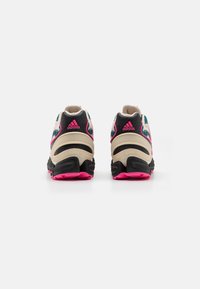 Black and beige athletic shoes with pink accents, featuring a textured upper, padded collar, and chunky sole for cushioning and support.
