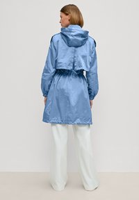 Giacca cropped azzurro chiaro con cappuccio, vita elastica e maniche lunghe. Texture liscia, design minimalista e vestibilità comoda.