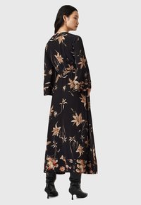 Vestido maxi negro de flores con mangas largas, que presenta una cintura ajustada y una falda fluida, adornado con patrones de flores en crema y rosa.