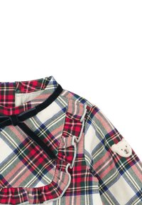 Kinderhemd mit kariertem Muster in Rot, Grün und Weiß; versehen mit einer schwarzen Samtschleife, Rüschen und einem Teddybär-Applikation am Ärmel.