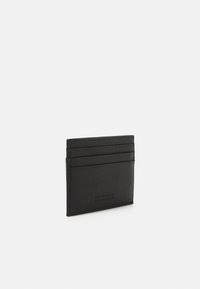 Black leather cardholder featuring four card slots, embossed logo details, slim design, and smooth texture.