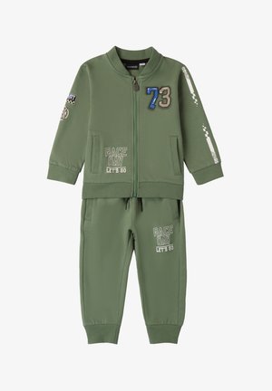 Completo tuta verde realizzato in tessuto morbido, con giacca a zip decorata da toppe e pantaloni della tuta abbinati con grafiche stampate.