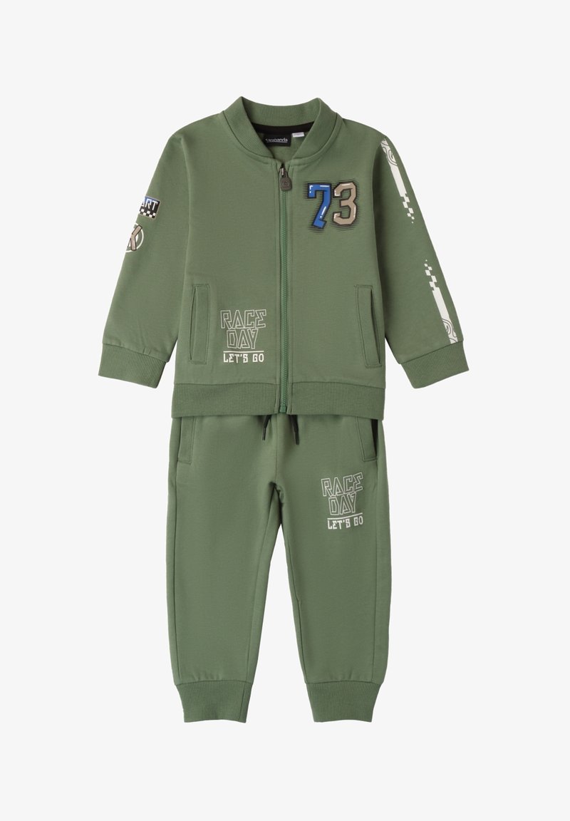 Zielony dres wykonany z miękkiego materiału, z kurtką zapinaną na zamek błyskawiczny z naszywkami oraz pasującymi spodniami dresowymi z nadrukowanymi grafikami.