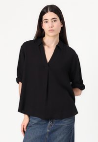 Black, short-sleeve, button-up shirt with a V-neck, made of a lightweight fabric; features rolled sleeves and a relaxed fit.