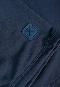 Mørkeblå stof med en glat tekstur, der har et firkantet logo i blåt gummi, sydde kanter og et rent design uden synlige mønstre.