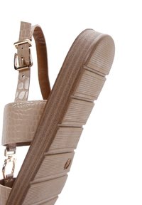 Beige platform sandal with a textured faux-crocodile upper, an adjustable ankle strap, and ridged rubber sole. Features gold-tone hardware.