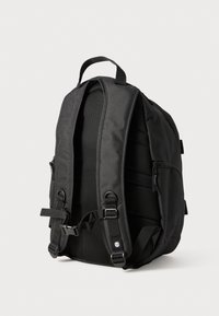 Zaino nero realizzato in tessuto resistente, dotato di spallacci imbottiti in rete, una maniglia superiore e tasche con zip ai lati.