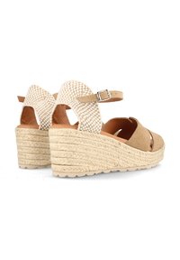 Sandalias de cuña en tono marrón con parte trasera de tela trenzada, diseño de punta abierta, tira en el tobillo y suela de plataforma de yute texturizado.