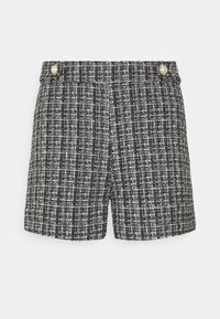 Shorts en tweed noir et blanc avec un motif texturé, présentant une coupe droite et deux boutons en perles en accent à la taille.