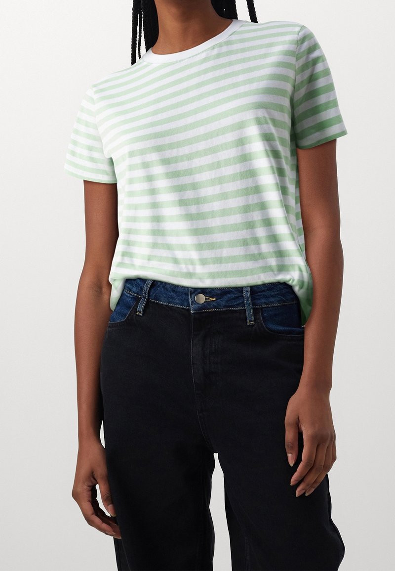Pruhované tričko ve světle zelené a bílé barvě, vyrobené z měkkého materiálu. Krátké rukávy, kulatý výstřih. Kombinováno s černými džíny s vysokým pasem.