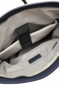 Interno della borsa in tessuto navy con fodera grigia chiara, dotato di tasca con zip, compartimento elastico e una piccola etichetta nera.
