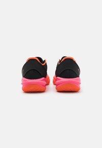 Scarpe da atletica nere con accenti arancioni, design elegante e suola rosa. Presentano una suola testurizzata per una migliore aderenza e una zona del tallone imbottita.