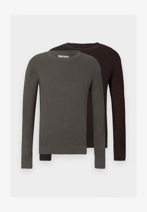 Du nuomojami raižyti megztiniai: vienas tamsiai alyvuogių spalvos, kitas tamsiai rudas. Abu turi apvalią apykaklę ir ilgas rankoves.