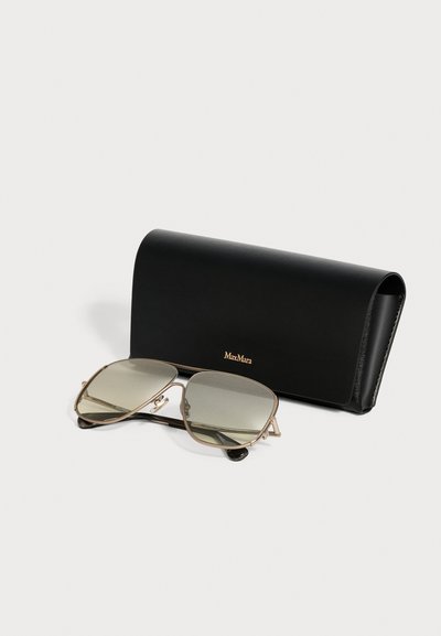 Une paire de lunettes de soleil à monture dorée avec des verres teintés devant un étui en cuir noir de marque MaxMara sur fond blanc.
