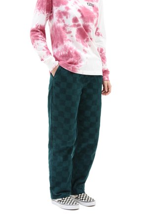 Grønne kordfløjspants med ternet mønster, parret med en tie-dye langærmet skjorte i pink og hvid, samt sort-hvide ternede sneakers.