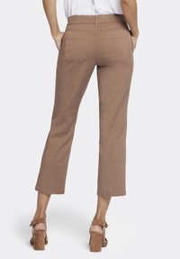 Pantalons cropped marron avec une texture lisse, dotés de deux poches arrière et d'une taille mi-haute, associés à des sandales à talons carrés beige.