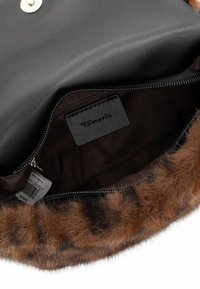Borsa in pelle nera con rifiniture in pelliccia sintetica marrone, dotata di interni con zip, rivestimento in tessuto e etichetta del marchio. La chiusura presenta un bottone a pressione in metallo.