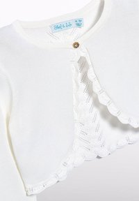 Cardigan bianco lavorato a maglia con bordo in pizzo ondulato, chiusura con bottoni frontale e dettaglio decorativo in oro. L'etichetta riporta "Heidi & Lulu."