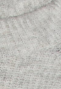 Tissu en tricot gris avec une texture douce, présentant un motif subtil de points en relief. Matériau léger et flexible.