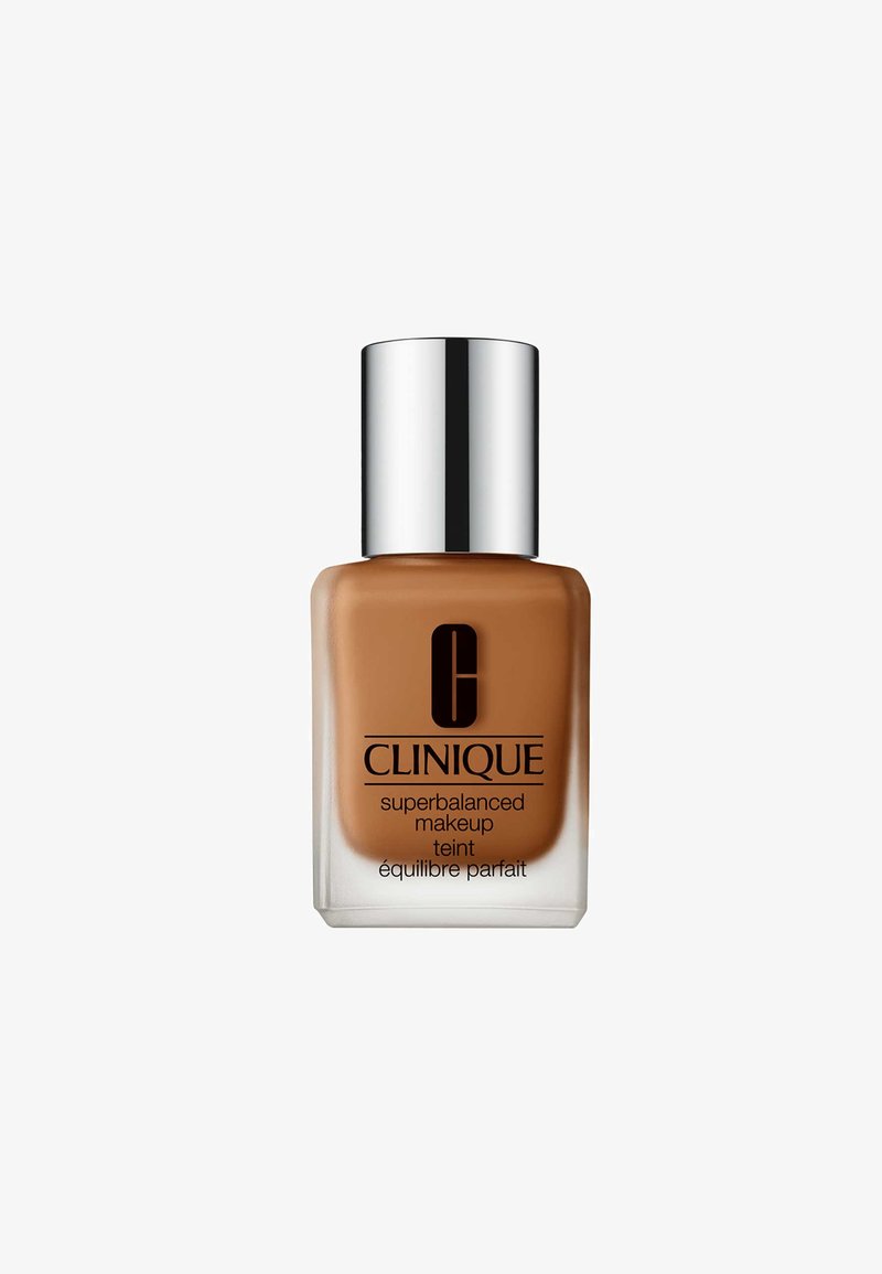 Clinique Superbalanced Makeup i en firkantet glassflaske med en polert sølvhette. Middels brun væske med en etiket som har svart tekst.